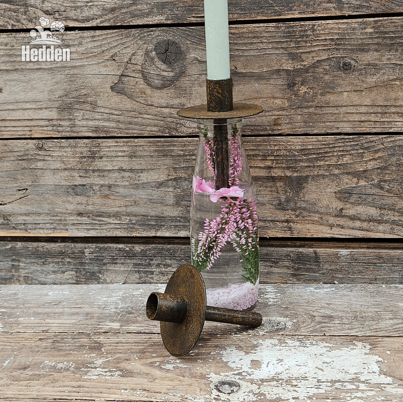 Klare Flasche, mit Trockenblumen innen drin und einem Kerzenhalter für Flaschen in rost-optil